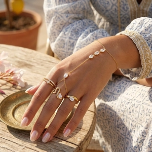 Detalle de una pulsera de mano de acero inoxidable dorado con anillos apilables y cristales