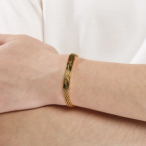 Détail d'un bracelet tissé en acier inoxydable doré pour homme avec plaque courbée