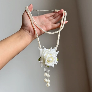 Close-up of double-layer pearl necklace with a delicate white rose pendant and tassels