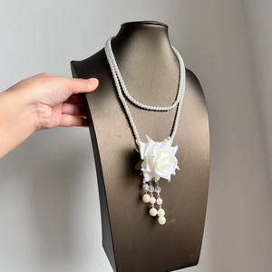 Close-up of elegant double-layer pearl necklace with white rose and tassel detail