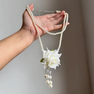 Close-up of double-layered pearl necklace featuring a large white rose pendant with tassels