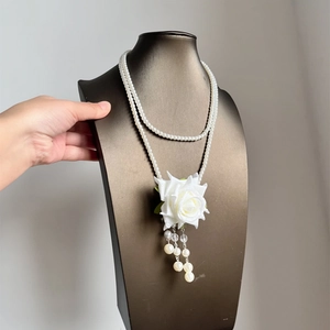 Close-up detail of elegant double-layered pearl necklace with white rose and tassels