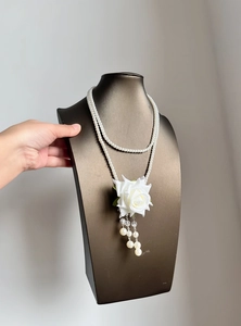 Detailed view of an elegant double-layered pearl necklace with a white rose tassel pendant