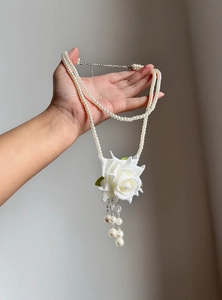 Detailed shot of a French style double-layered pearl necklace with a white rose pendant