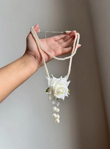 Elegant double-layered pearl necklace featuring a white rose pendant and pearl tassels detail