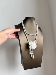 Detailed view of white rose pendant and pearl tassels on elegant double-layer necklace
