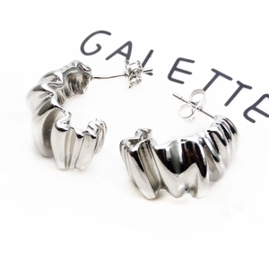 Detailed macro view of silver plated croissant style earrings with pleated metal texture