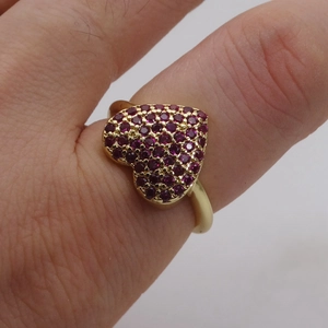 Macro di anello a cuore dorato con zirconi fucsia micro-pavimentati indossato