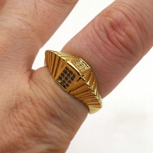 Dettaglio anello a sigillo dorato con micro pavé di zirconi e design quadrato a strati