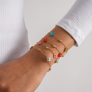 Primer plano de elegantes pulseras de acero inoxidable con flores de colores y circones