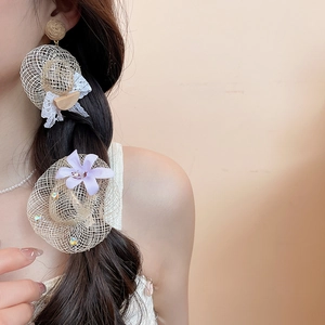 Détail de boucles d'oreilles en chapeau de paille et accessoire floral pour les vacances
