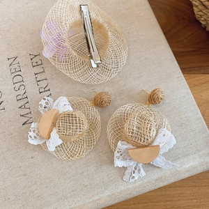 Vue détaillée des boucles d'oreilles chapeau en raphia avec nœuds en dentelle et clip