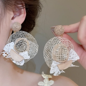 Vue détaillée de boucles d'oreilles en raphia avec dentelle blanche et détails en bois