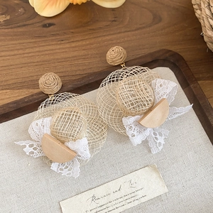 Détail de boucles d'oreilles chapeau de paille avec nœuds en dentelle pour la plage.