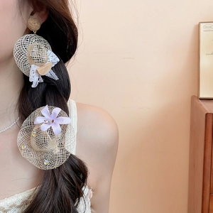 Détail d'un mannequin portant des boucles d'oreilles chapeau en raphia et un ensemble floral
