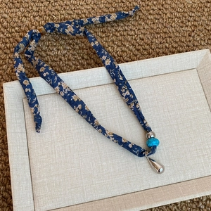 Dettaglio della collana foulard a fiori blu con ciondolo a goccia d'acqua in argento