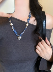 Primo piano di una collana a foulard in seta floreale blu con pendente a cuore