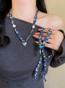 Dettaglio della collana foulard di seta a fiori blu con ciondolo a cuore