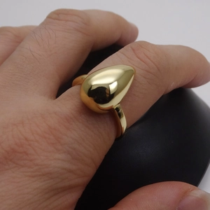 Close-up of minimalist water drop ring with polished 14k gold finish on a model hand