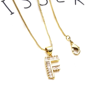 Foto macro de un collar dorado con colgante de letra F y circonitas en cadena box