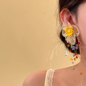 Detailopname van kuststijl gele bloem oorbel met kleurrijke kralen kwastjes op model.