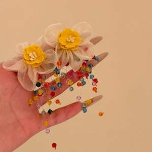 Detailweergave van kleurrijke kralenkwastoorbellen met gele stoffen bloemen