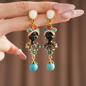 Close-up of vintage resin portrait earrings with colorful rhinestones and silver needles.