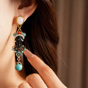 Close-up of vintage resin portrait drop earring with turquoise and rhinestone detailing