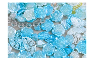 Dettaglio macro di ciondoli in resina perlata con rose e farfalle per creazioni artigianali