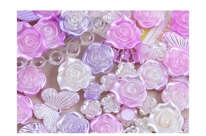 Dettaglio di ciondoli in resina perlata a forma di rosa e farfalla per decorazioni