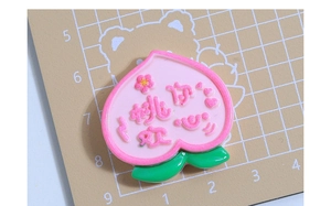 Gros plan d'un accessoire en résine pêche avec texte 3D mignon et détails fleuris
