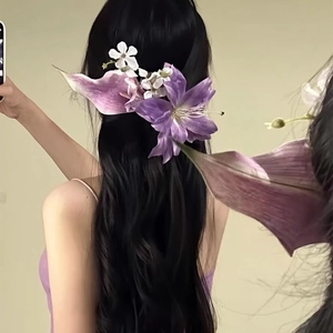 Macro shot of an elegant purple lily flower hair clip on long wavy black hair detail view