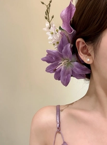 Detail view of a purple lily flower hair clip worn for a traditional Chinese hairstyle.