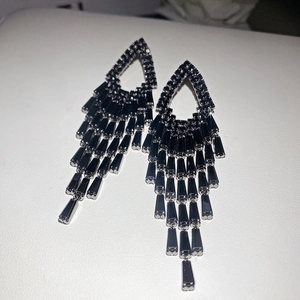 Vue détaillée d'élégantes boucles d'oreilles noires à pompons avec zircons noirs brillants.