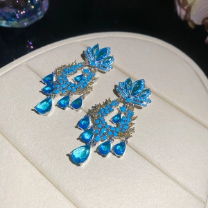 Detailed close-up of luxury blue zircon teardrop chandelier earrings on jewelry pad.