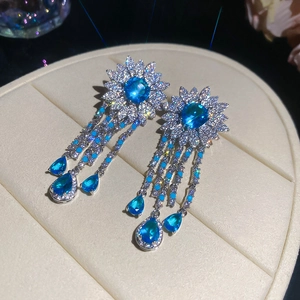 Close-up of elegant silver earrings featuring blue zircon sunflower and teardrop tassels