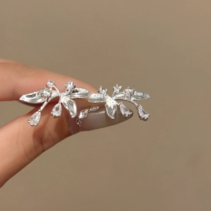 Dettaglio di eleganti orecchini a fiore in argento con brillanti zirconi a goccia.