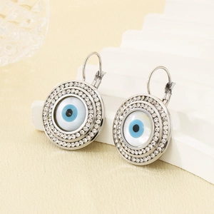 Détail de boucles d'oreilles œil protecteur en acier titane avec strass brillants