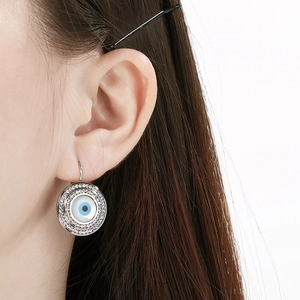 Détail de boucles d'oreilles Mauvais Œil en acier titane avec cristaux pavés portées par un mannequin