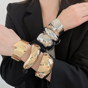 Stylish chunky polished metal cuff bangles in gold and silver stacked on model arms