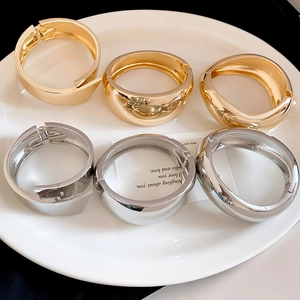 Close-up detail of assorted metallic glossy gold and silver bangles arranged on a white plate