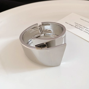 Detailed macro view of a silver metallic wrap bangle with a high-gloss geometric finish
