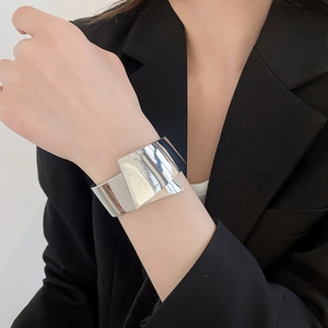 Close-up of minimalist silver metallic shiny cuff bracelet worn with a black blazer