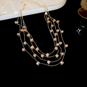 Close-up van een elegante gelaagde gouden ketting met roze zirkonia steentjes.
