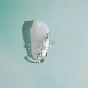 Detailed view of silver-toned stainless steel zirconia earrings set on a white shell.