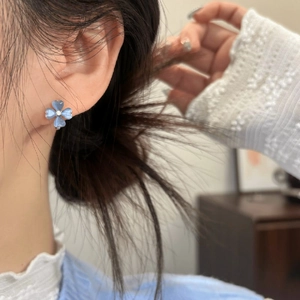Detailed close-up showing an ice blue translucent flower stud earring on a female ear