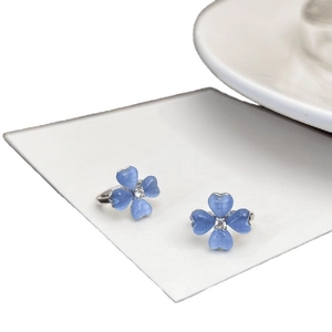 Elegant blue cat-eye stone flower stud earrings displayed on a minimalist white card