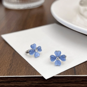 Ice blue flower earrings detail view showing cat-eye stone petals and central sparkling crystal.