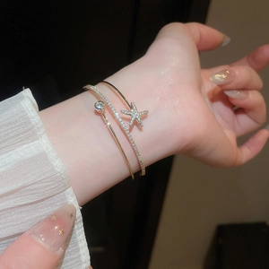 Detailed view of an elegant gold double-layer open bangle with a sparkling starfish charm