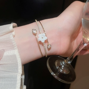 Close-up of elegant double-layer open bangle with mother-of-pearl flower and zircons.